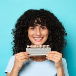 patient holding a porcelain veneer shade guide for smile enhancement consultation
