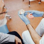 dentist explaining denture types and benefits to a senior patient
