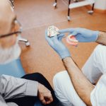 dentist explaining denture types and benefits to senior patient